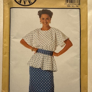 May include: A vintage Simplicity sewing pattern featuring a woman modeling a two-piece outfit. The outfit includes a white top and a blue skirt, both with a polka dot pattern. The pattern number is 9490, and the size is RR (14-20).