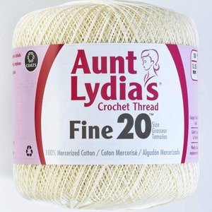 Puede incluir: Una madeja de hilo de crochet Aunt Lydia's Fine 20 de color crema. La etiqueta dice "Aunt Lydia's Crochet Thread Fine 20" y "100% Mercerized Cotton/Coton Mercerisé/Algodón Mercerizado".