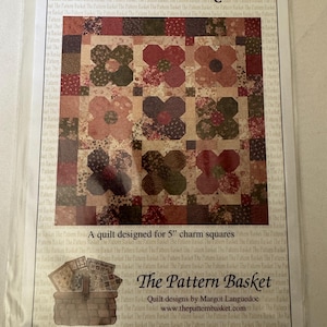 May include: A quilt pattern titled "Flower Box" featuring a floral design. The quilt top is made of various fabric squares in shades of red, brown, and green. The pattern is designed for 5-inch charm squares.