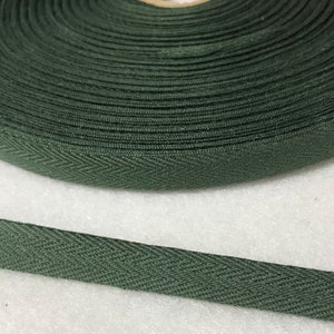 Op de afbeelding: Een rol donkergroen katoenen twillband met een herringbone-patroon. De band is ongeveer 2,5 cm breed.