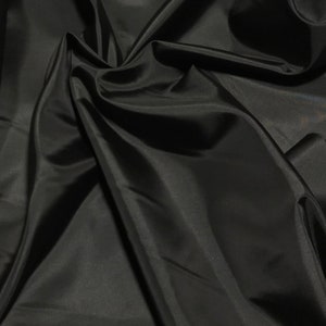 May include: Black satin fabric with smooth, flowing folds. The fabric is soft and luxurious, with a subtle sheen.