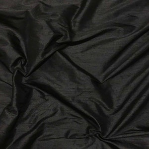 Puede incluir: Tela de seda negra con un acabado liso y brillante. La tela est&aacute; drapeada y doblada, mostrando su textura y ca&iacute;da.