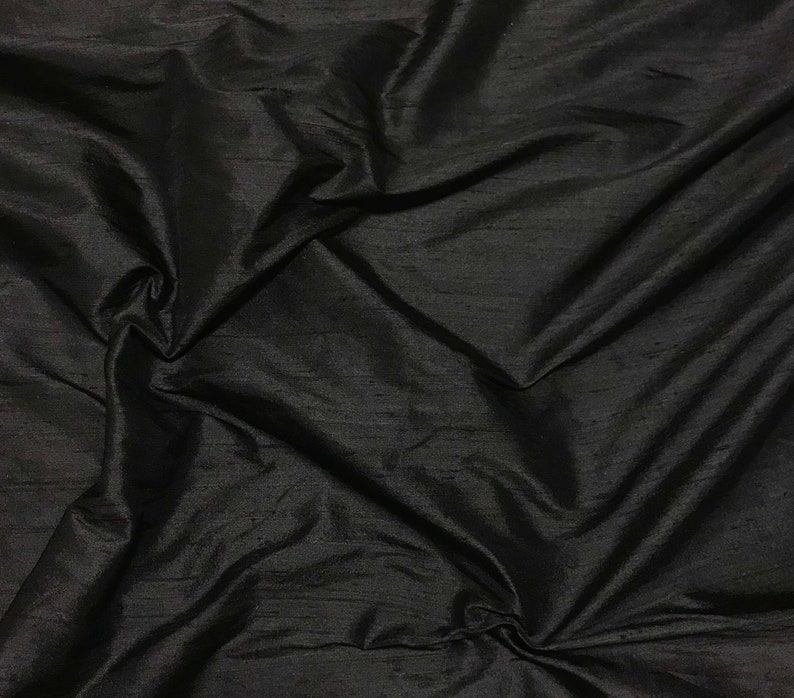 Puede incluir: Tela de seda negra con un acabado liso y brillante. La tela est&aacute; drapeada y doblada, mostrando su textura y ca&iacute;da.