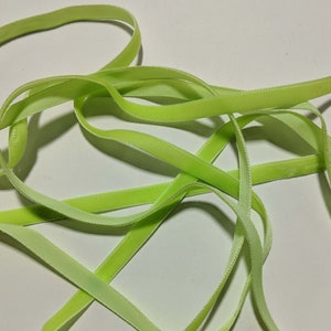 May include: A close-up of a light green velvet ribbon. The ribbon is soft and has a subtle sheen.
