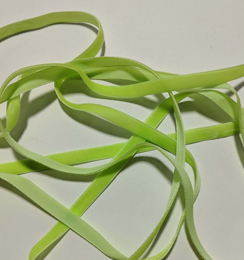 May include: A close-up of a light green velvet ribbon. The ribbon is soft and has a subtle sheen.