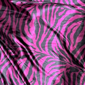 Può includere: Tessuto rosa e nero con motivo a zebre. Il tessuto è stropicciato e ha un aspetto setoso.