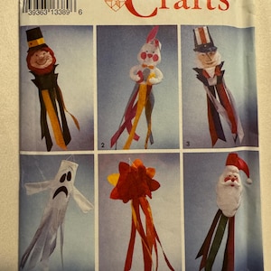 May include: Simplicity Crafts pattern featuring six whimsical craft designs. The designs include a leprechaun, a bunny, Uncle Sam, a ghost, a starburst, and Santa Claus, each with colorful ribbon streamers. The pattern is one size.