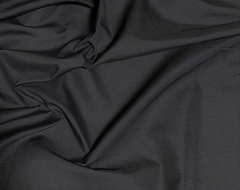 Può includere: Tessuto nero con una texture liscia e senza pieghe. Il tessuto è piegato e drappeggiato, mostrando la sua natura morbida e fluida.