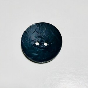 May include: A black button with a textured surface and two holes.