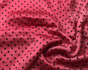 May include: Pink fabric with black polka dots. The fabric is smooth and has a slight sheen.