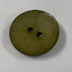 May include: A two-hole green button with a textured surface.