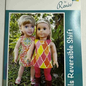 May include: A book cover featuring two dolls wearing colorful dresses. The text "Creative Cards by Renée" is at the top, with "Dolls Reversible Shift" on the side. The dolls are standing in front of a green background.