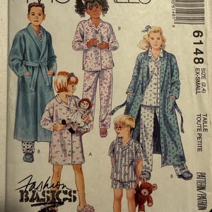 May include: McCall's sewing pattern for children's sleepwear and robes. The pattern features illustrations of children in various pajama sets and robes. The text "Fashion Basics for Kids" is visible, along with size and pattern details.