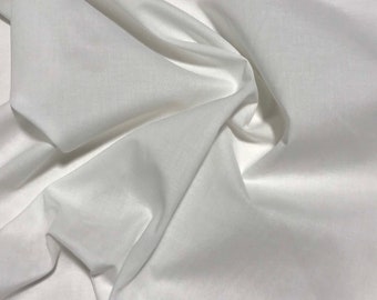 May include: White cotton fabric with a smooth texture and a soft drape. The fabric is folded and arranged to show its texture and drape.