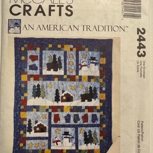 May include: A McCall's Crafts pattern envelope featuring a winter-themed quilt design. The quilt design includes snowmen, trees, houses, and mittens, set against a blue background with yellow stars. The text "AN AMERICAN TRADITION" is visible.