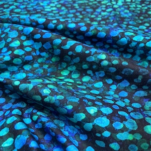 May include: Close-up of a fabric with a pattern of blue and teal circles on a black background. The fabric is folded, showing the texture and depth of the material. The design is reminiscent of water or a night sky.