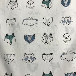 May include: White fabric with a repeating pattern of various animal faces in black and blue. The animals include foxes, raccoons, badgers, hedgehogs, and otters.