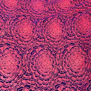 May include: A close-up of a fabric with a repeating pattern of pink flowers on a dark blue background. The flowers are outlined in black and have a layered, dimensional look.