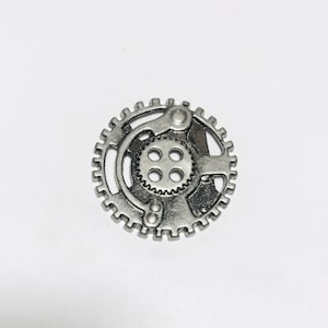 以下が含まれることがあります： 中央に小さな歯車と側面にレバーが付いた銀色の金属製の歯車チャーム