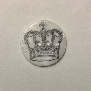 May include: White button with a black and white crown design. The button has two holes.
