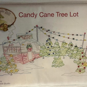 May include: An embroidered design featuring a Christmas scene with a candy cane, a snowman holding a banner that says "Trees", and a camper selling fresh cut trees. The text "Candy Cane Tree Lot" is displayed at the top.
