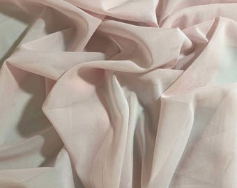 Könnte beinhalten: Nahaufnahme eines weichen, hellrosa Stoffes mit einer glatten, seidenartigen Textur. Der Stoff ist drapiert und gefaltet, wodurch ein fließender und eleganter Look entsteht.
