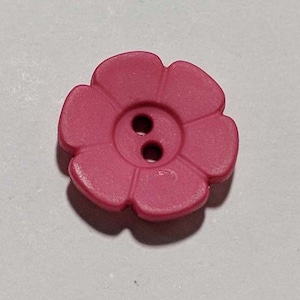 May include: A pink plastic flower-shaped button with two holes.