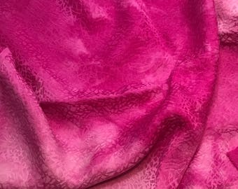 May include: A close-up of a pink fabric with a textured, cracked pattern. The fabric is soft and flowing, with a gradient of color from a darker pink to a lighter pink.