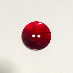 May include: A two-hole red shell button with a shiny finish.