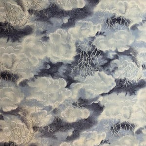 May include: A fabric pattern featuring a dark navy blue and light blue sky filled with fluffy white clouds and intricate, branching white lightning bolts. The design creates a stormy atmosphere with layered cloud formations and sharp electrical strikes.