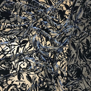 Puede incluir: Tela de terciopelo negro con una superposición transparente con un patrón floral. La tela está drapeada y texturizada, mostrando el diseño intrincado.