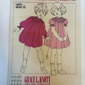 May include: Vintage sewing pattern for a girl's peasant dress. The cover features illustrations of two young girls wearing dresses. The text reads "GIRL'S PEASANT DRESS" and "size 6". The pattern is from Grace L. Knott Smocking Supplies Ltd.