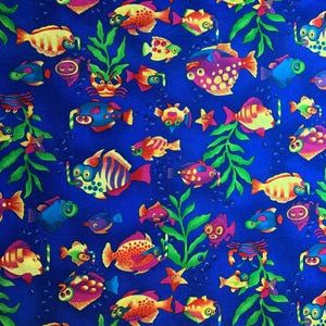 May include: A vibrant blue fabric featuring a repeating pattern of colourful cartoon fish, crabs, and starfish swimming among green seaweed. The fish are depicted in various shades of yellow, orange, pink, and blue, with bubbles scattered throughout.