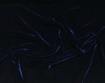 Op de afbeelding: Een close-up van een donkerblauwe fluwelen stof met een gladde, zachte textuur. De stof is gedrapeerd en gevouwen, wat een luxe en elegante uitstraling creëert.