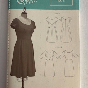 May include: A sewing pattern packet from Colette Patterns, featuring a dress design labeled "Rue" and size range 0-26. The packet has a teal and white color scheme, with a dress form and illustrations of the dress.
