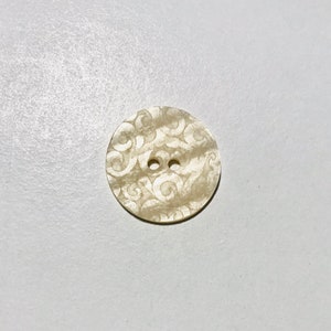 May include: A white button with a swirl pattern and two holes.