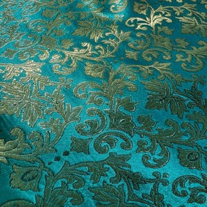 May include: Teal fabric with a gold embossed floral pattern. The fabric has a subtle sheen and a luxurious feel.