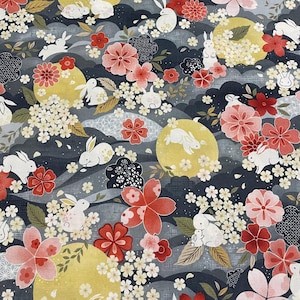 May include: A fabric pattern featuring a repeating design of white rabbits, yellow moons, and various flowers in shades of red, pink, and white. The background is a dark blue with cloud-like shapes.