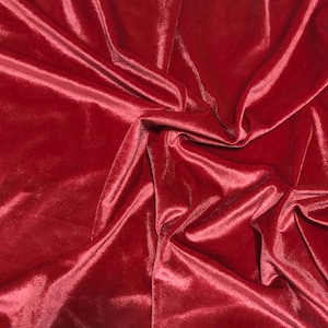 May include: Close-up of a luxurious, draped fabric in a deep burgundy color. The material has a soft, velvety texture with subtle highlights and shadows, suggesting a rich, plush textile. The folds and creases add depth and dimension.