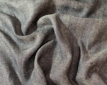 Può includere: Primo piano di un tessuto a spina di pesce nero e bianco. Il tessuto è tessuto con una texture sottile e ha una sensazione morbida e fluida.