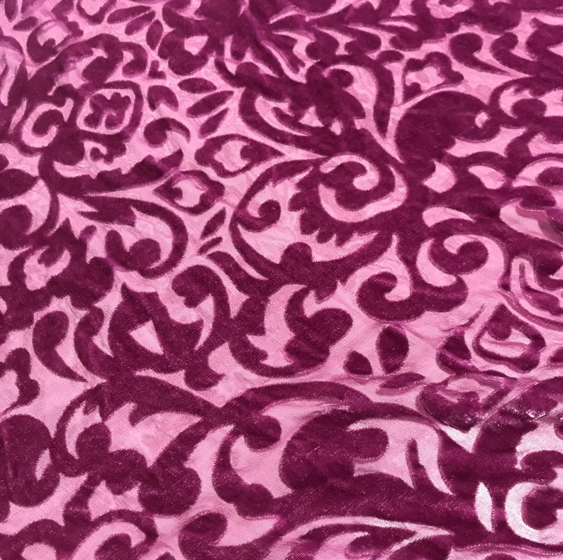 May include: Purple velvet fabric with a pink background and a damask pattern.