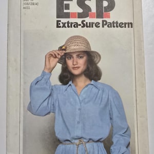 May include: Vintage Simplicity sewing pattern showing a woman in a blue dress and straw hat. The pattern is labelled "ESP Extra-Sure Pattern" and includes size "N" for sizes 10, 12, and 14. The price is marked as 95 cents.
