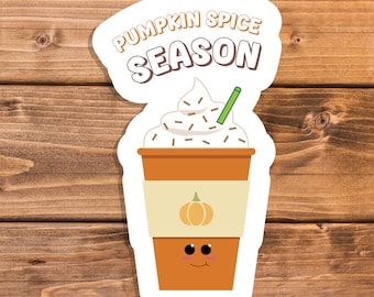 Op de afbeelding: Een sticker met een cartoon pompoen kruiden latte met slagroom, chocoladesnippers en een groen rietje. De beker heeft een lachend gezicht en een pompoenafbeelding. De tekst "PUMPKIN SPICE SEASON" staat boven de beker.
