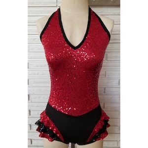 May include: Red sequined halter top with a black trim and a black ruffled skirt.