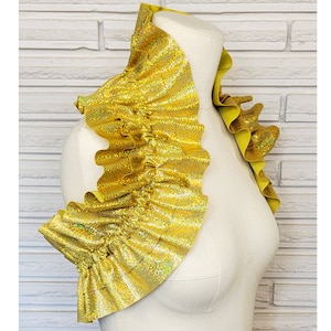 May include: A gold, glittery, ruffled collar with a wide, rounded neckline. The collar is made of a soft, flexible material and is perfect for adding a touch of sparkle to any outfit.