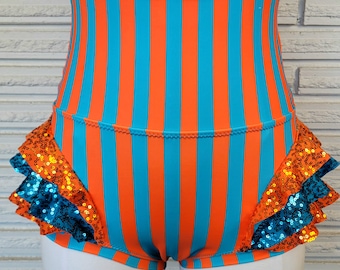 May include: High-waisted shorts with a blue and orange striped pattern and a ruffled trim with sequins. The ruffles are layered and have a turquoise and gold color scheme.