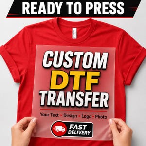 May include: A bright red t-shirt featuring a clear, rectangular DTF transfer sheet placed on the front. The sheet displays the bold text CUSTOM DTF TRANSFER in white and yellow, followed by Your Text, Design, Logo, Photo and a delivery icon.