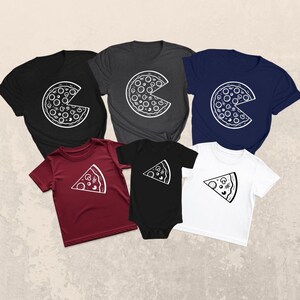 May include: A collection of black, charcoal, navy, burgundy, and white t-shirts and a black onesie. Each garment features a white pizza graphic. The t-shirts display a whole pizza with a bite taken out, while the onesie and one t-shirt show a pizza slice.