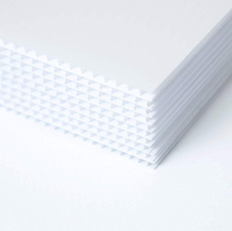Peut inclure: Une pile de feuilles de plastique ondul&eacute; blanc. Les feuilles sont textur&eacute;es avec un motif en grille.
