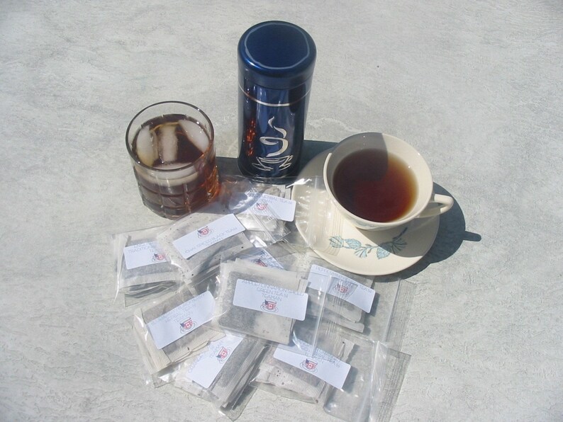 Peut inclure: Une bo&icirc;te &agrave; th&eacute; bleue avec un motif blanc, une tasse de th&eacute;, un verre de th&eacute; glac&eacute; et un tas de sachets de th&eacute;. Les sachets de th&eacute; sont emball&eacute;s individuellement dans du plastique transparent et portent une &eacute;tiquette blanche avec du texte noir.